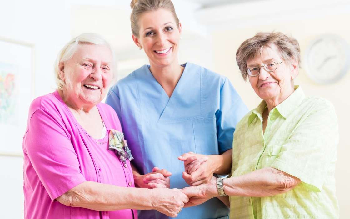 Betreuungskraft begleitet Senior beim sicheren Gehen im Flur einer hellen Wohnung mit guter Beleuchtung