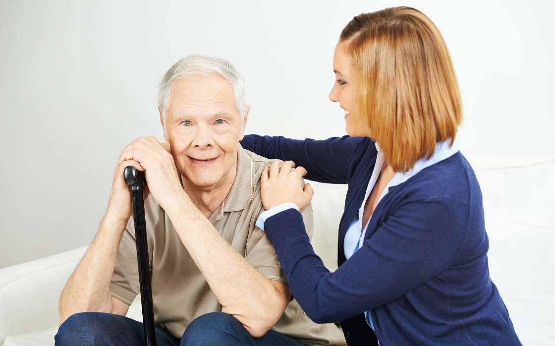 Betreuungskraft begleitet einen demenzkranken Senior im vertrauten Zuhause