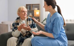 Betreuungskraft hört mit Seniorin mit Demenz Musik und blättert in einem Fotoalbum