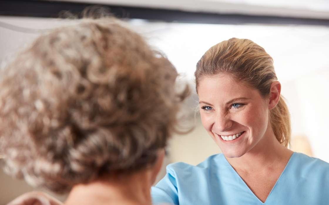 Angehörige sprechen mit Betreuungskraft im Wohnzimmer über Betreuung zu Hause