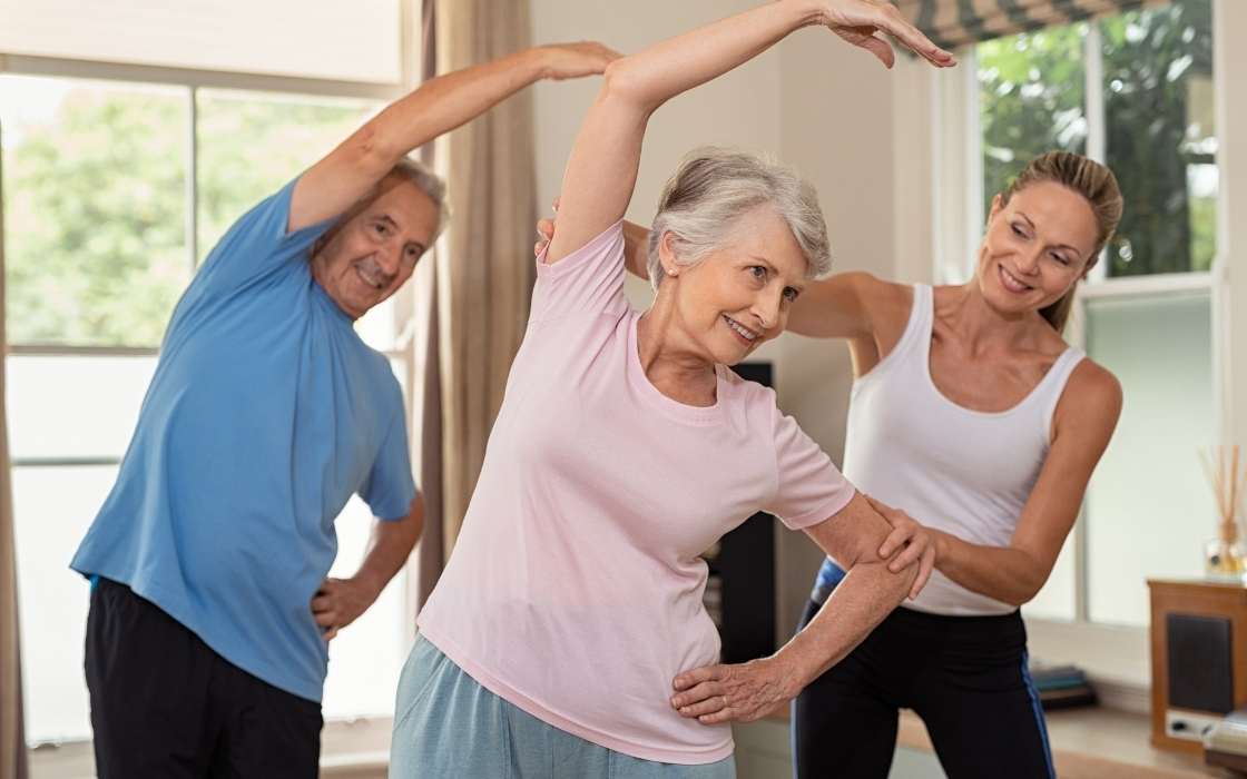 Seniorin macht leichte Gymnastikübungen zuhause im Wohnzimmer