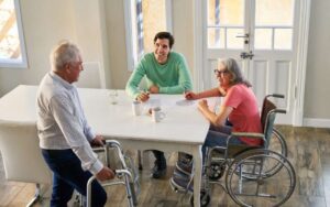 Mehrere Senioren sitzen gemeinsam in einer Wohnküche und sprechen über den Alltag in ihrer Wohngemeinschaft